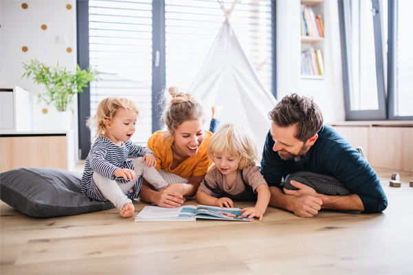 a happy family with children lays on the floor reading picture books.