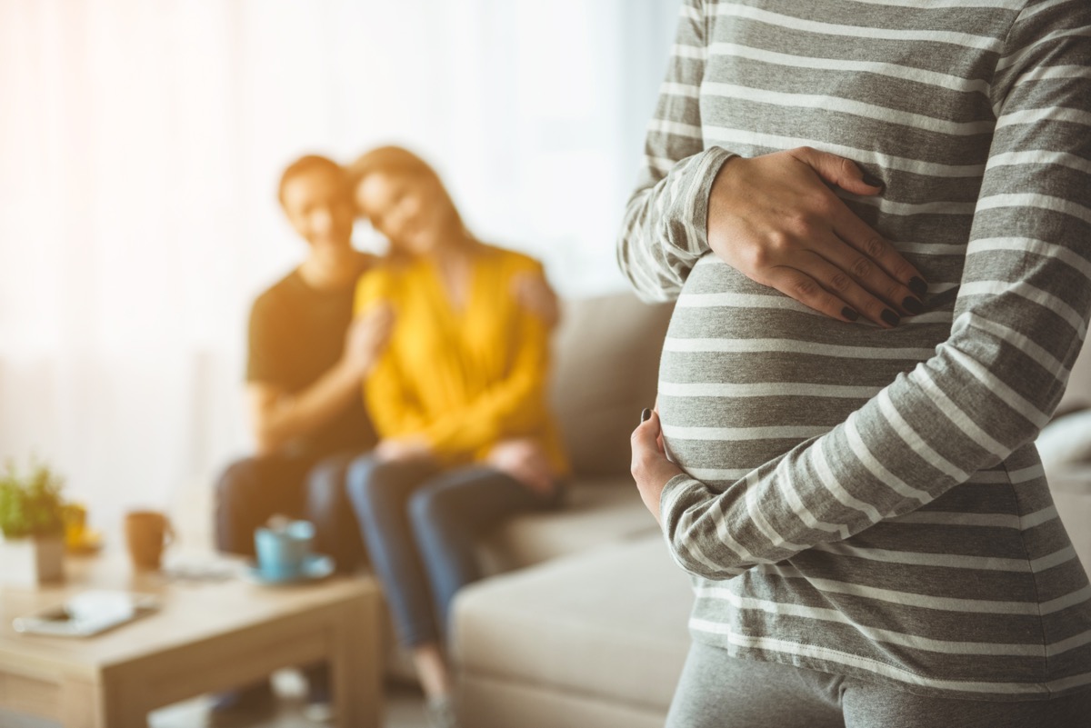 a happy couple looks on from their couch at their surrogate